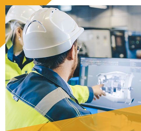 Workers in safety gear reviewing a computer screen